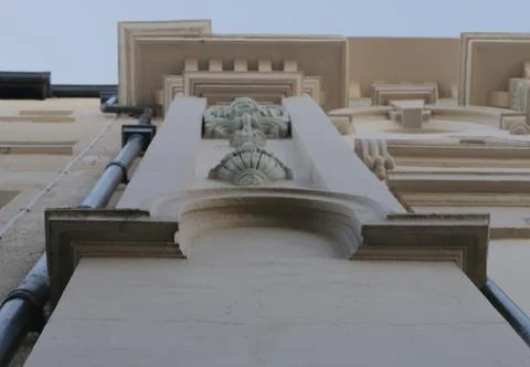 Looking up the side of a building with a statue Stock Photos