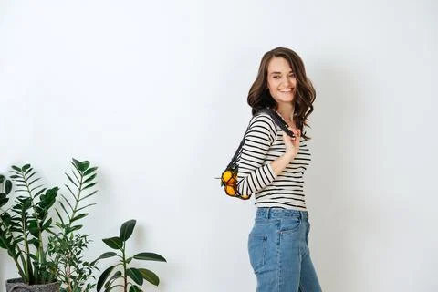 Looking to the side smiling brunette posing with net bag with tangerines Stock Photos