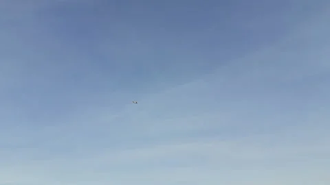 Looking up to the sky where a tiny airplane flying high above open airspace. Stock Footage 327901717