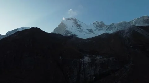 Looking up at snowcapped mountain peak with thin whispy clouds driving away  Stock Footage 252378025