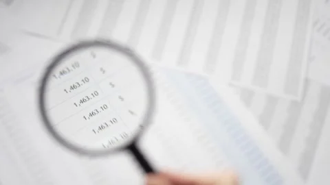 Looking at a Spreadsheet With Magnifying Glass Closeup Stock Footage 255991767