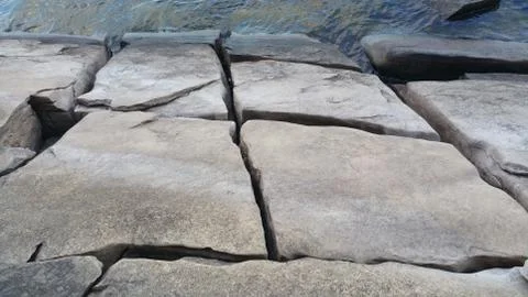 Looking at square rocks from the forest on the edge of a lake Foto stock