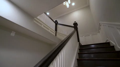 Looking up a staircase with dark handrail and white spindles Stock Footage 345692122