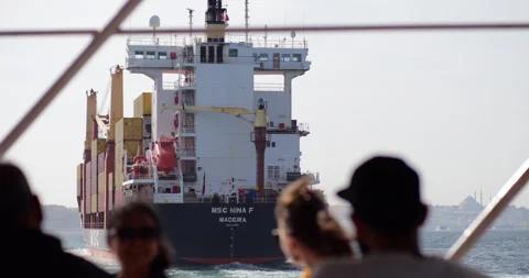 Looking to stern of container ship from ferry, blurred people on foreground Stock Footage 318682285