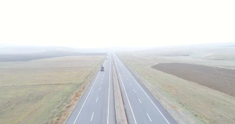 Looking straight at traffic on a county highway though foggy clouds. 4K Aerial Stock Footage 99725438