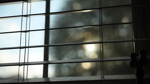 Looking at sunset through window closed by blinds and sun rays Stock Footage 296086683