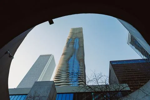 Looking up at a tall, wavy building through a circular opening. Other tall bu Stock Photos