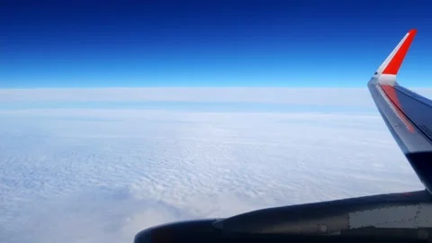 Looking through an airplane window while flying in a wing with a beautiful blue Stock Footage 166316815
