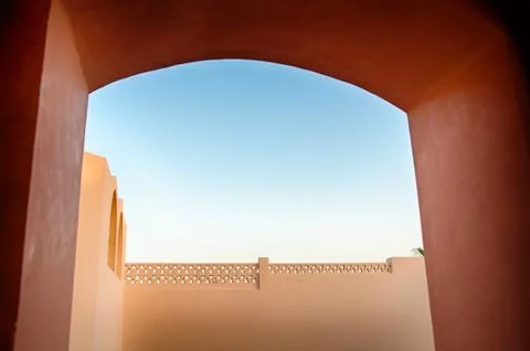 Looking through archway at wall and blue sky 스톡 사진