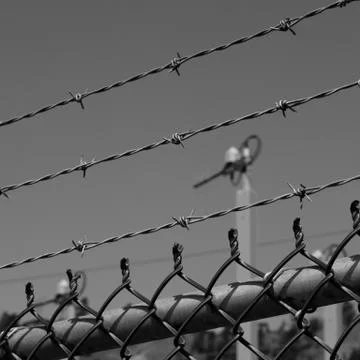 Looking through barb wire security fence Stock Photos