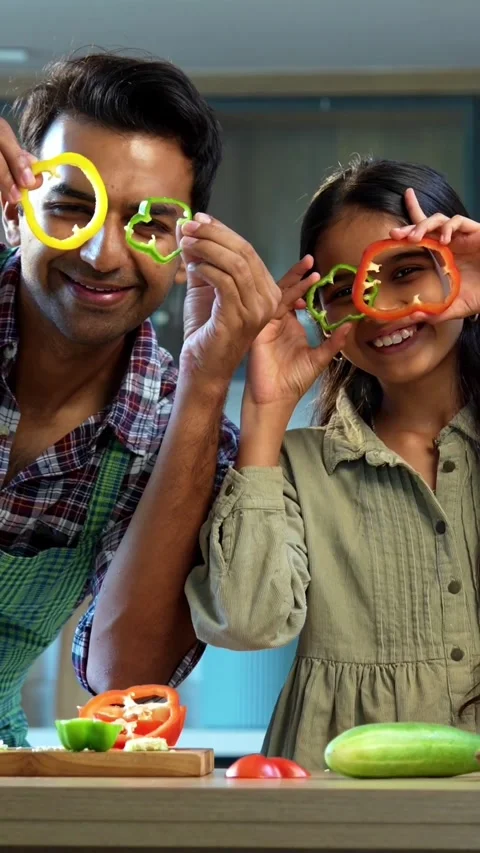 Looking through capsicum rings, father daughter enjoying bonding in kitchen Video stock 342843753