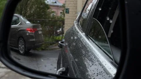 Looking through a car side window covered in raindrops at a parked dark vehicle Stock Photos