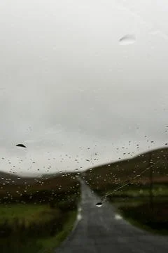 Looking through a car window blurred by raindrops. As a road crosses a moorland Stock Photos