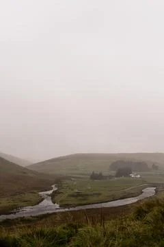 Looking through a car window. As a river meanders past a farm house Stock Photos