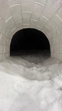 Looking through circular white snowy arched pathway entrance tunnel Stock Photos