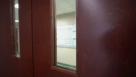 Looking through classroom windows to a hooded figure carrying a rifle 60fps.mp4 Stock Footage 339007942