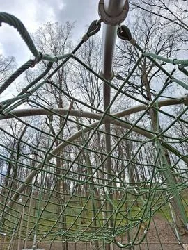 Looking up through a climbing net dome in a forest playground during daytim.. 写真素材