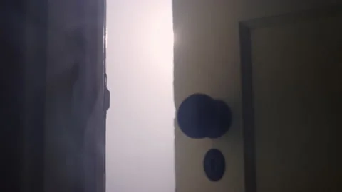 Looking through a crack in the door into a room filled with white creepy smoke Stockbeeldmateriaal 134300074
