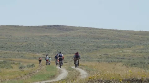 Looking through heat waves as mountain biker ride away on prairie road Stock Footage 74790873