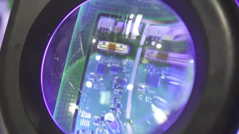 Looking through a magnifying glass on a printed circuit board to detect Stock Footage 252534592