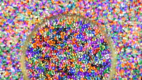 Looking Through a Magnifying Glass of a Rotating Bead With Colored Transpare Stock Footage 225894558