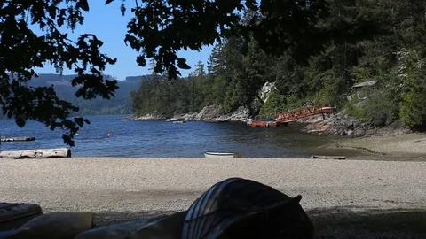 Looking Through Trees Onto A Beautiful Beach Scene With A Boat Video stock 99940284