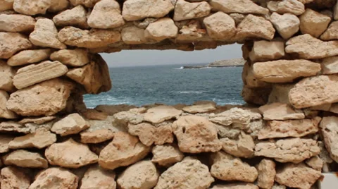 Looking through whole in wall to view sea and a island Stock Footage 36556644