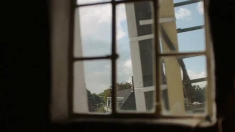 Looking through a window at a church while the sails of a windmill pass by Stock Footage 85214540
