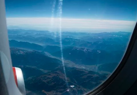 Looking through the window of the plane during the flight to the snow-capped  Stock Photos