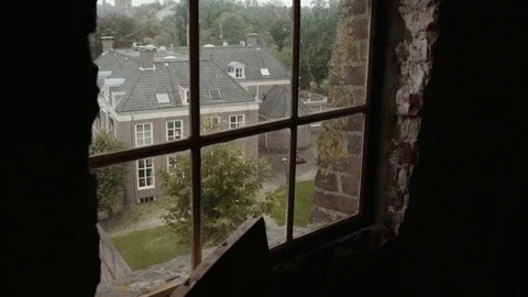 Looking through a window towards a house while the sails a windmill pass by Stock Footage 85215655