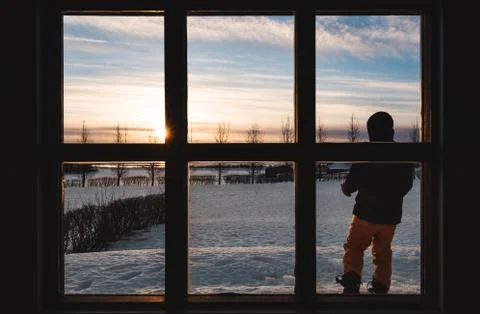 Looking through window in winter sunrise, with a man standing alone in morning Stock Photos