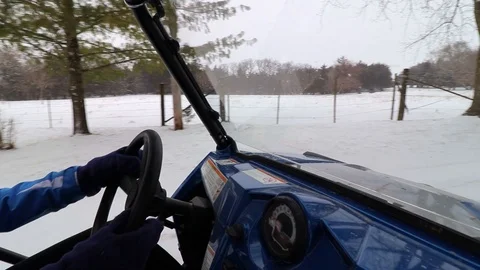 Looking through the windshield of a side-by-side ATV driving down a snowy road. Stock Footage 119972487