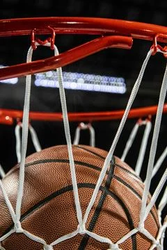 Looking up at the top of a basketball falling through the net with arena lights Foto stock