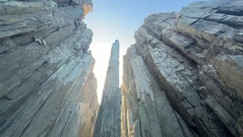 Looking up at the Totem Pole sea stack between towering cliffs Stock Footage 347435022