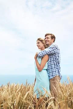 Looking towards their future. a young couple in a field on a sunny day. Stock Photos