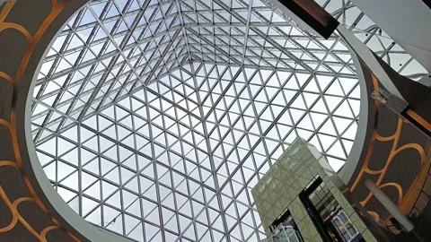 Looking from under the ceiling of a mall building with a modern triangular de Stock Footage 219814717