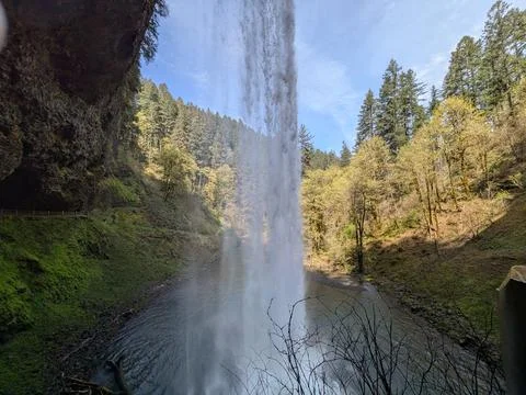 Looking upward from beneath a towering waterfall, water crashes Stockfoto's