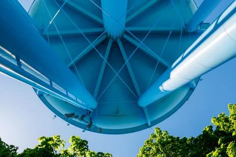 Looking up at a water tower under a clear blue sky surrounded by green trees Fotos Stock