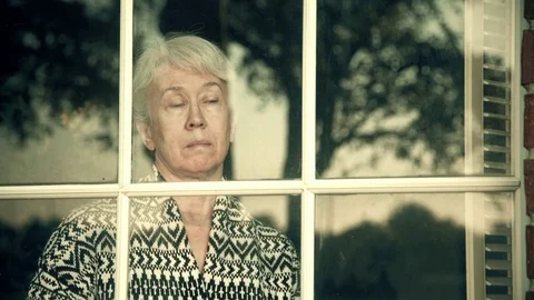 Looking in from a window to a worried older woman 4k Stock Footage