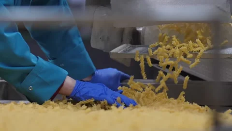 Looking on the worker hands in blue gloves that controls quality of a pasta Video stock 263018633