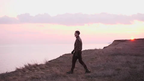 Looking on young biker in leather suit going to a precipice above sea in sunset Stock Footage 152865535
