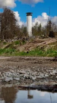 Lookout tower in the forest reflected in a puddle on the starse 스톡 사진