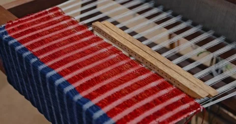 Loom weaving red and blue fabric, traditional textile production Stock Footage 343057517