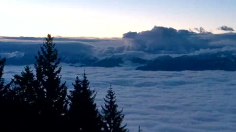 Looming menacing clouds over the mountains and very thick white and blue fog Stock Footage 256157141