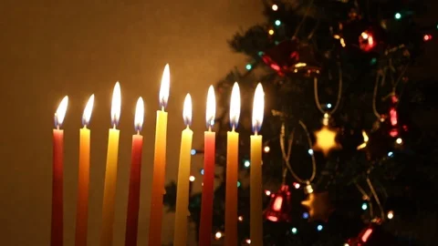 Loop - Hanukkah candles burning next to a decorated Christmas tree Stock Footage 120731391