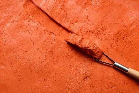 Loop tool slicing orange clay surface, closeup Stock Photos