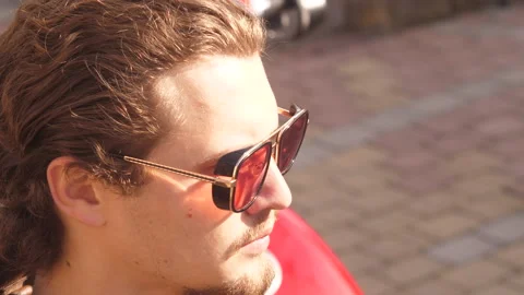Loop video of curly young man in biker suit put on his red glasses and put's off Stock Footage 152739487
