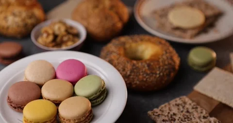 Looping macro of plate with macarons, bagel and walnuts on dark rustic tablet Stock Footage 320166785