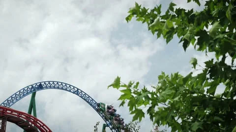 Looping rollercoaster attraction against blue sky. People riding rollercoaster Stock Footage 196156179