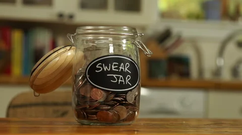 Loose change put in a saving jar, reading Swear Jar Video stock 44116860